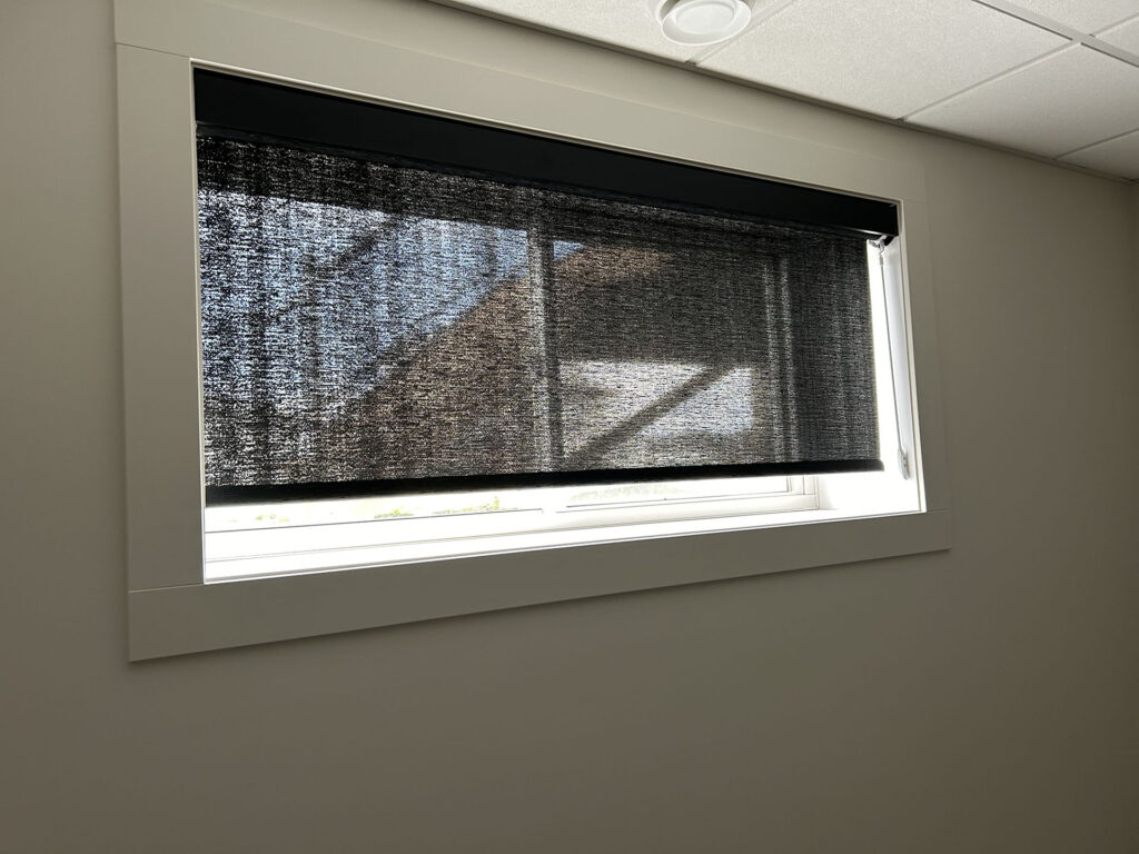Dark Woven Solar Roller Shade Mounted in White Window Frame
