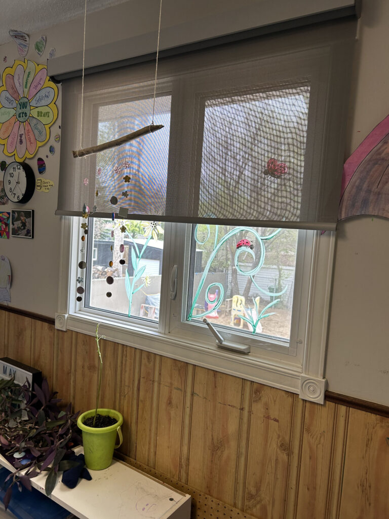 Daycare Window with Light-Filtering Shade and Hanging Decor