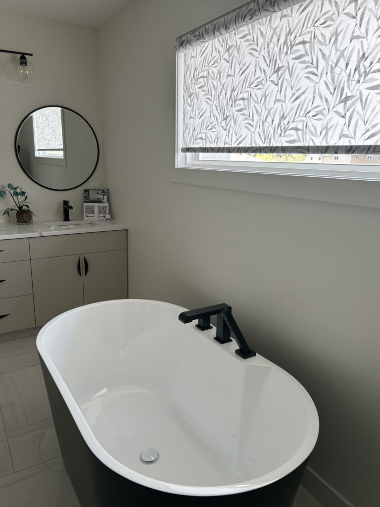 Freestanding Soaking Tub Beneath Window with Leaf-Patterned Roller Shade